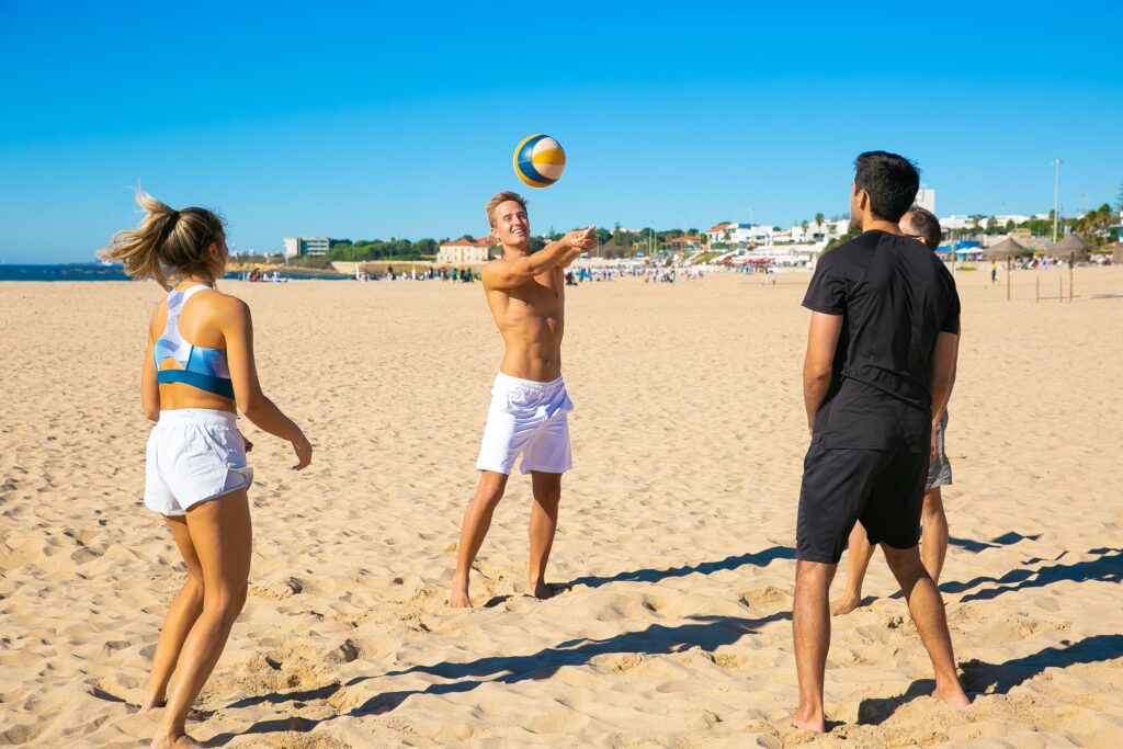 chicos internacionales jugando al voleibol en la playa