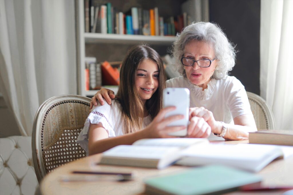 un ejemplo de los beneficios de las relaciones intergeneracionales,una abuela aprendiendo a usar un smartphone gracias a una chica joven 