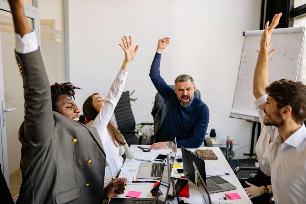 Equipo de trabajo diverso celebrando un logro en la oficina. Esta imagen refleja el éxito de la diversidad empresarial y la inclusión en el lugar de trabajo.